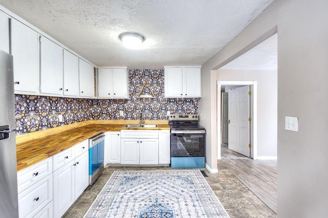 kitchen featuring white cabinetry, butcher block counters, stainless steel appliances, sink, and backsplash