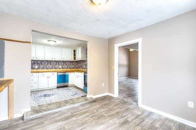 kitchen with light hardwood / wood-style flooring, wooden counters, tasteful backsplash, dishwasher, and white cabinets