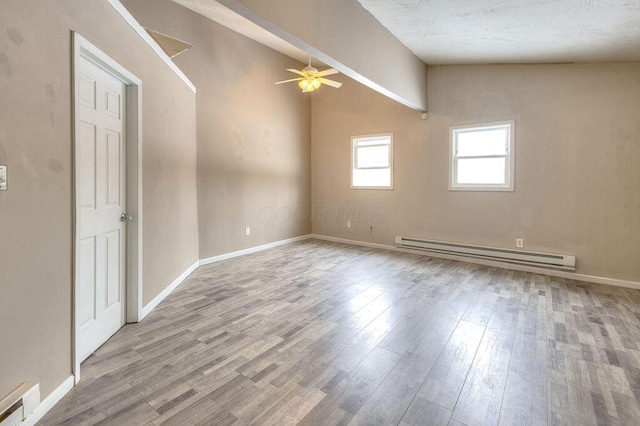 empty room featuring ceiling fan, a baseboard heating unit, a textured ceiling, and light hardwood / wood-style floors