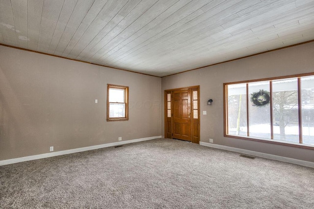 empty room featuring wood ceiling, crown molding, and carpet flooring