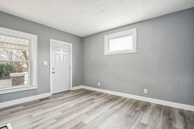 unfurnished room with a textured ceiling and light hardwood / wood-style floors