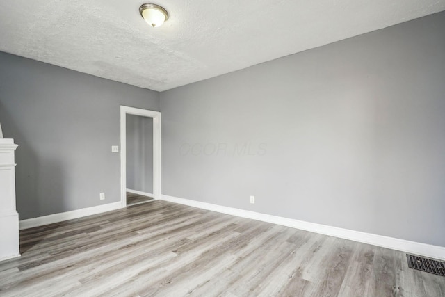 empty room featuring a textured ceiling and light wood-type flooring