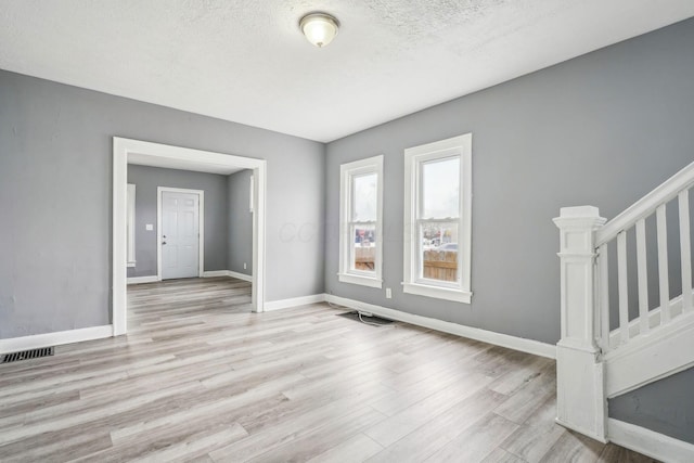 unfurnished room with light hardwood / wood-style flooring and a textured ceiling