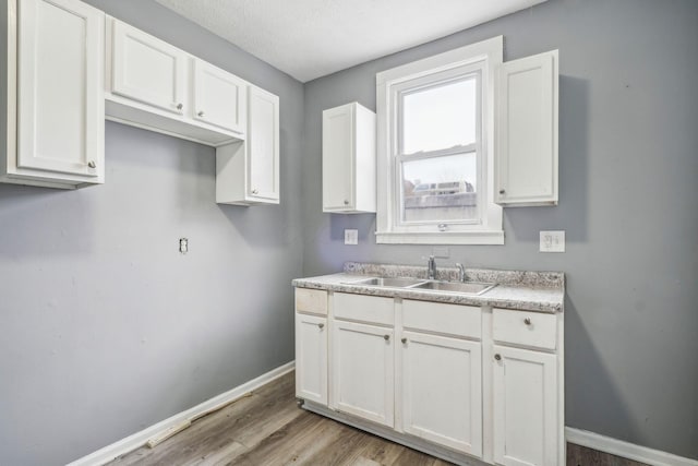 kitchen featuring white cabinetry, sink, and light wood-type flooring