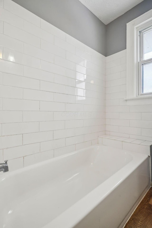 bathroom featuring a washtub, hardwood / wood-style floors, and a textured ceiling