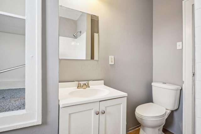 bathroom featuring vanity, walk in shower, and toilet