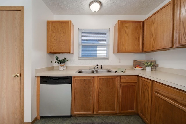 kitchen featuring stainless steel dishwasher, sink, dark tile patterned floors, and a textured ceiling