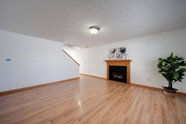 unfurnished living room featuring a textured ceiling and light hardwood / wood-style floors