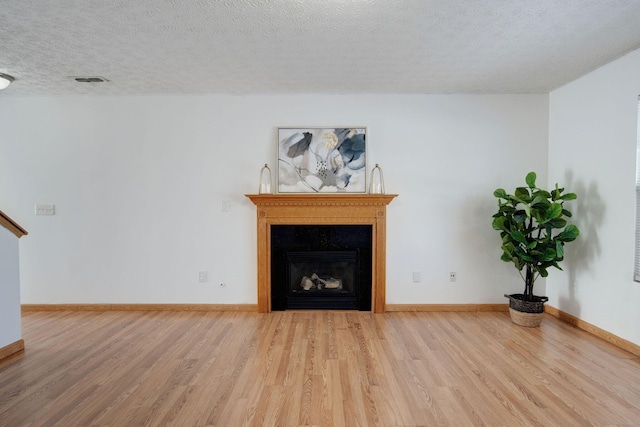 unfurnished living room with a textured ceiling and light hardwood / wood-style flooring