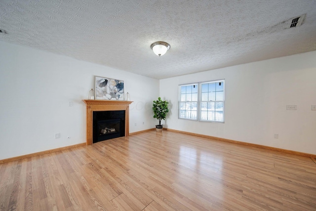 unfurnished living room with a textured ceiling and light wood-type flooring