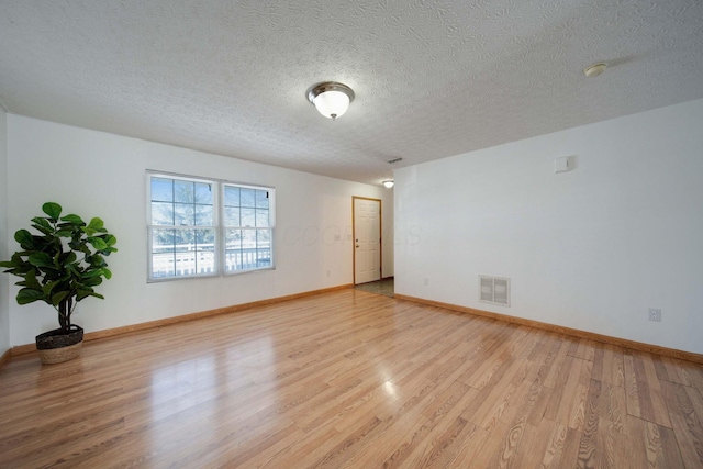 spare room with a textured ceiling and light hardwood / wood-style floors