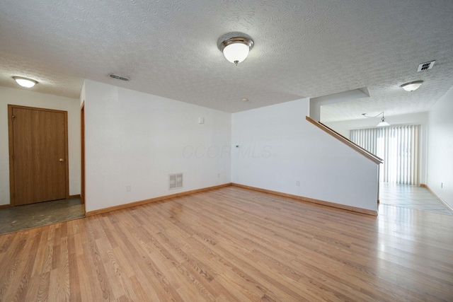 empty room featuring a textured ceiling and light hardwood / wood-style flooring