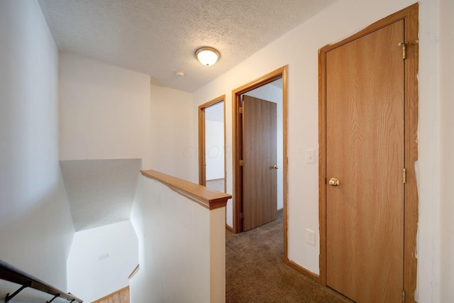 hall featuring light colored carpet and a textured ceiling