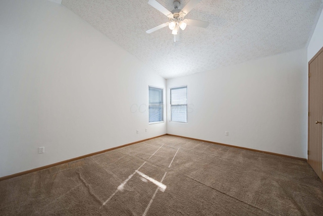 carpeted spare room featuring ceiling fan, vaulted ceiling, and a textured ceiling