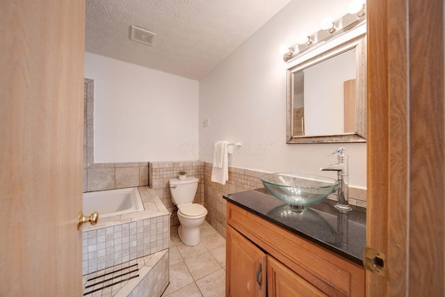 bathroom with toilet, tile patterned flooring, a relaxing tiled tub, and a textured ceiling