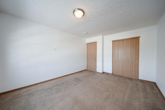 unfurnished bedroom featuring a textured ceiling, a closet, and light carpet