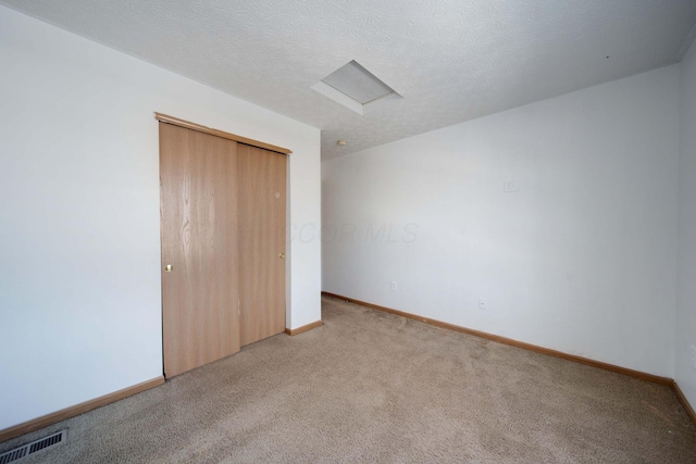 unfurnished bedroom with light colored carpet, a closet, and a textured ceiling