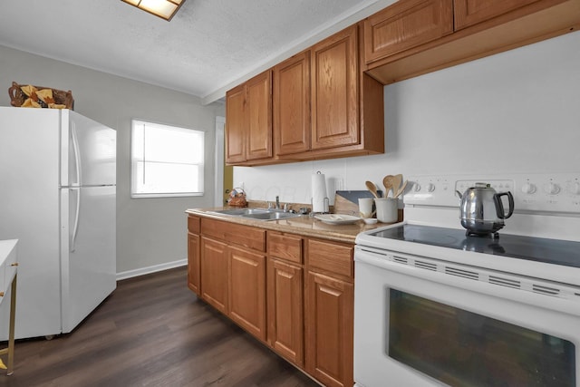 kitchen with white appliances, brown cabinets, dark wood-style flooring, a textured ceiling, and a sink