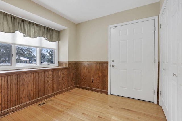 entryway featuring light wood-type flooring and wood walls