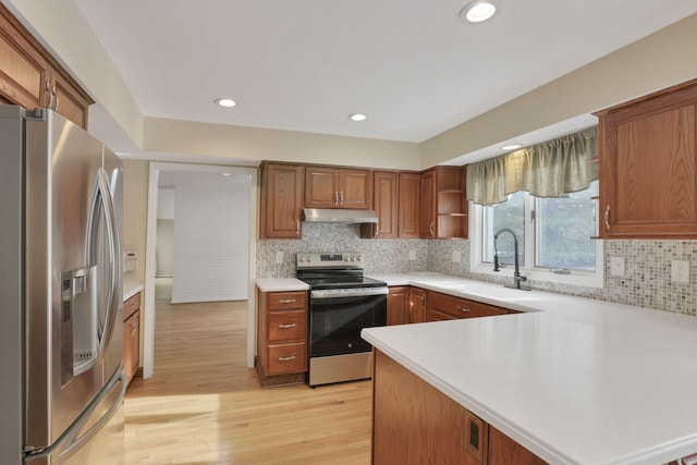 kitchen featuring sink, decorative backsplash, kitchen peninsula, stainless steel appliances, and light wood-type flooring