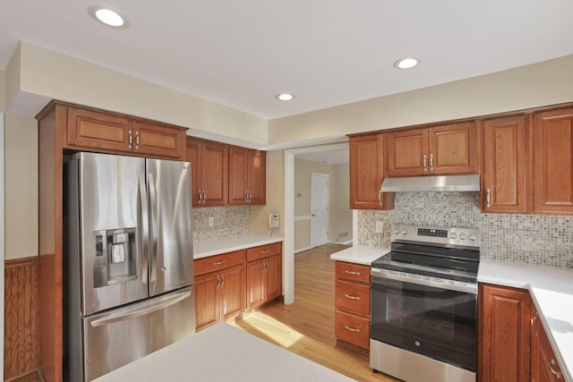 kitchen with appliances with stainless steel finishes, light hardwood / wood-style flooring, and backsplash