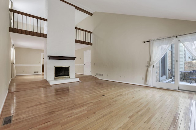 unfurnished living room featuring beam ceiling, a fireplace, high vaulted ceiling, and light wood-type flooring