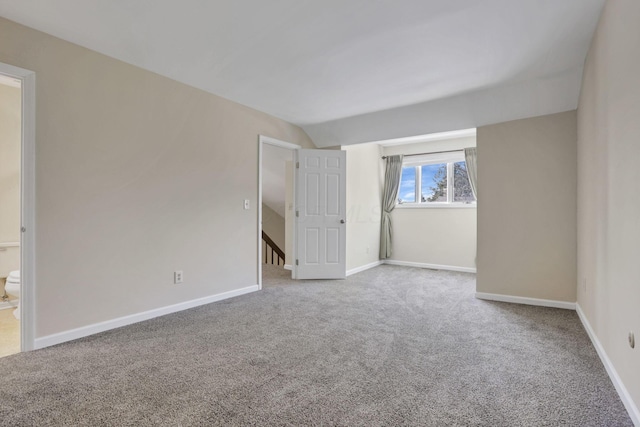 carpeted empty room featuring vaulted ceiling