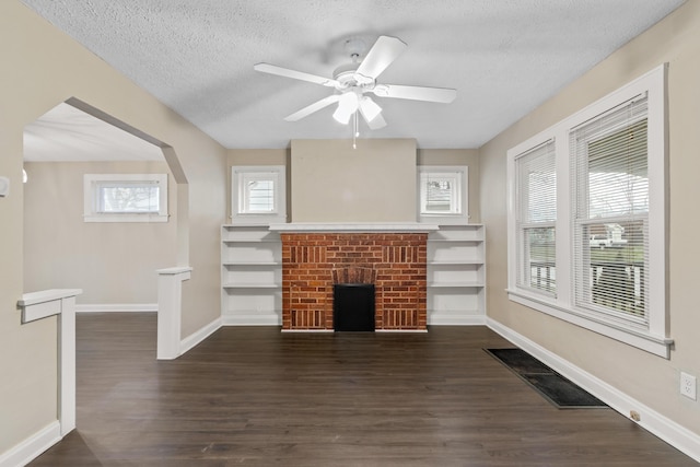 unfurnished living room featuring dark hardwood / wood-style flooring, ceiling fan, a fireplace, and a textured ceiling