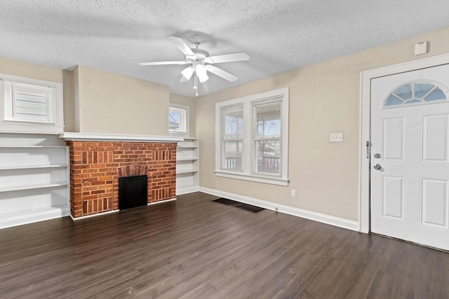 unfurnished living room with dark hardwood / wood-style flooring, ceiling fan, a fireplace, and a textured ceiling