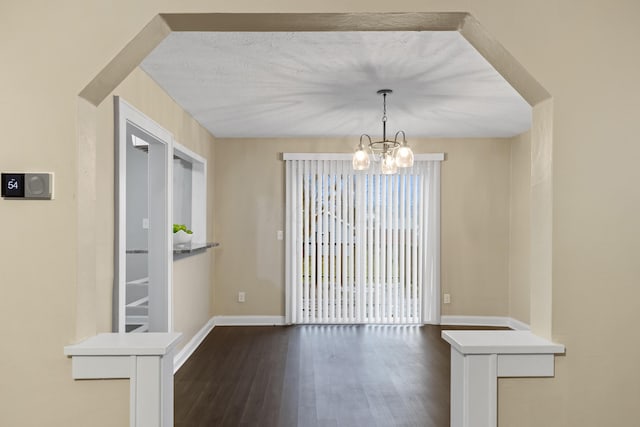 unfurnished dining area featuring a notable chandelier and dark wood-type flooring