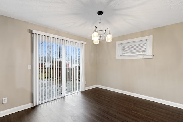 unfurnished room with a textured ceiling, a notable chandelier, and dark hardwood / wood-style flooring