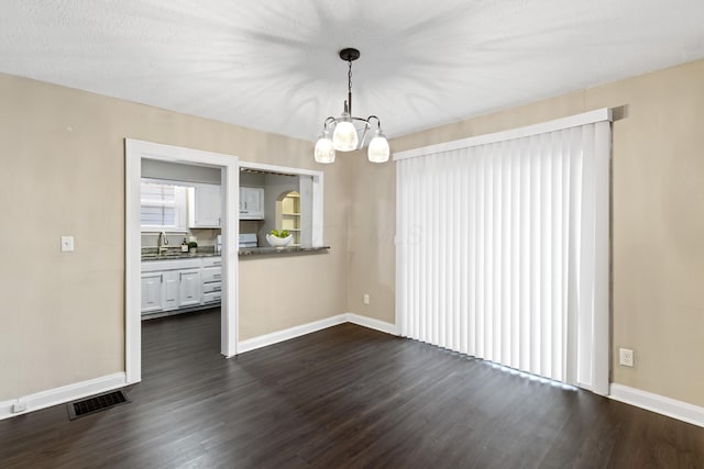 unfurnished dining area with dark wood-type flooring, sink, and a chandelier