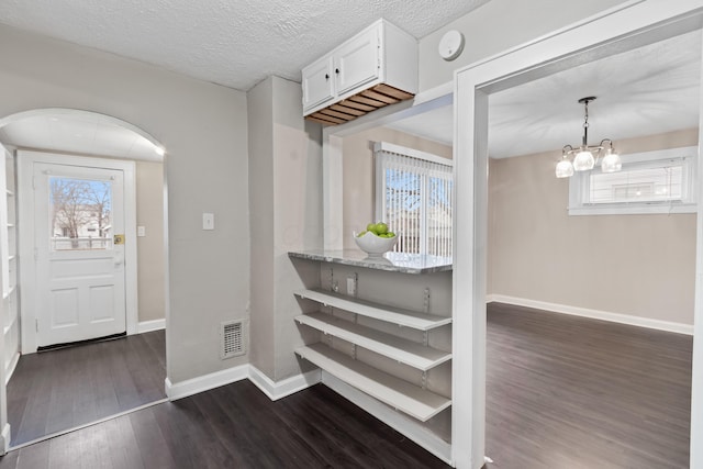 entrance foyer featuring dark hardwood / wood-style flooring, a notable chandelier, and a textured ceiling