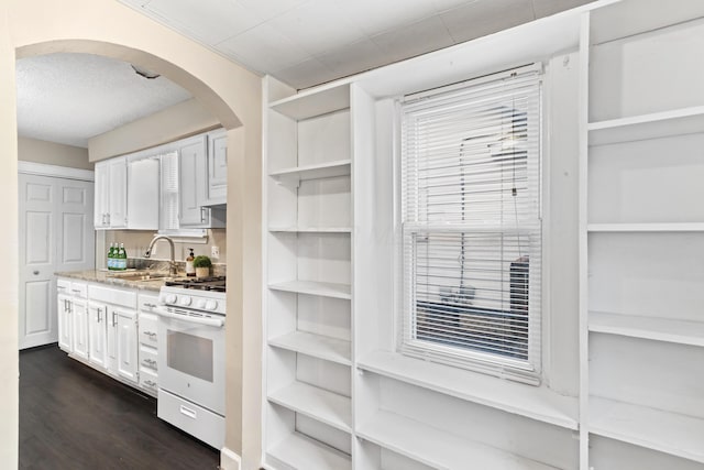 kitchen with dark hardwood / wood-style floors, sink, white gas range oven, and white cabinets