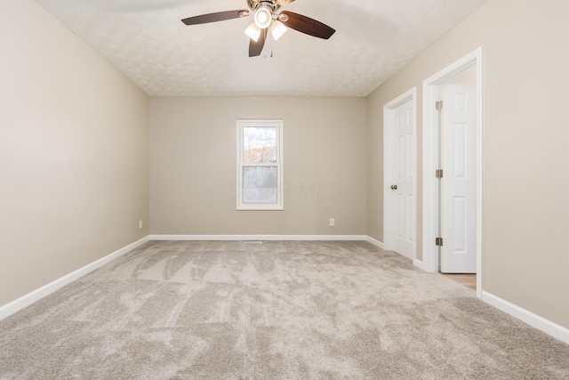 unfurnished room featuring ceiling fan, light colored carpet, and a textured ceiling