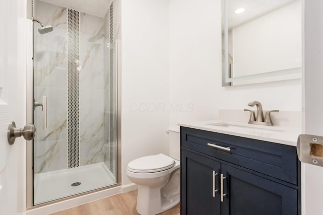 bathroom with wood-type flooring, an enclosed shower, vanity, and toilet