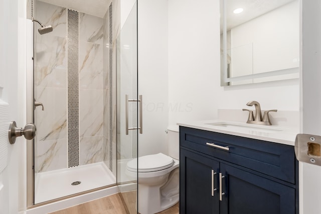 bathroom featuring toilet, a shower with shower door, wood-type flooring, and vanity