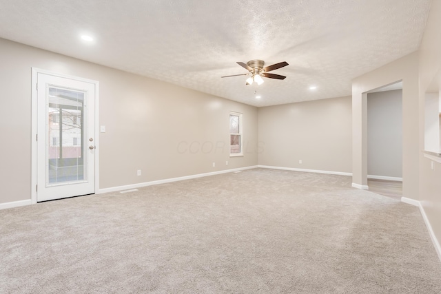 spare room with ceiling fan, light carpet, and a textured ceiling