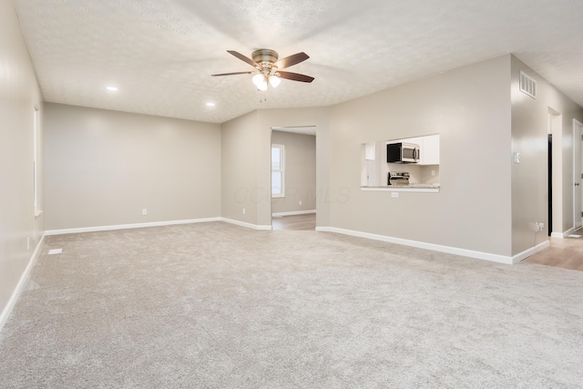 carpeted spare room featuring ceiling fan and a textured ceiling