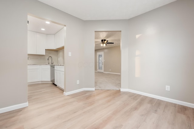 kitchen featuring ceiling fan, light hardwood / wood-style floors, stainless steel dishwasher, sink, and white cabinets