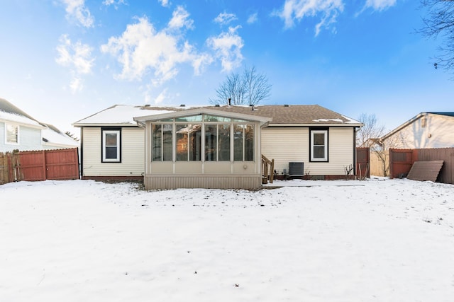 snow covered rear of property featuring a sunroom and cooling unit