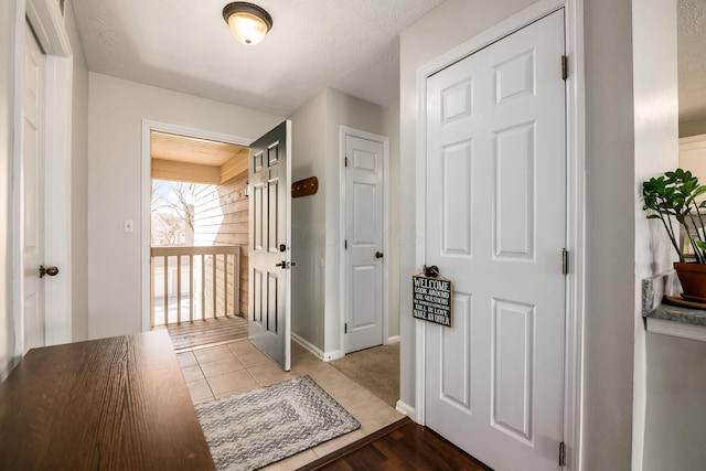 doorway with light tile patterned floors and a textured ceiling