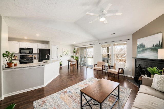 living room with sink, ceiling fan, dark hardwood / wood-style floors, a textured ceiling, and vaulted ceiling