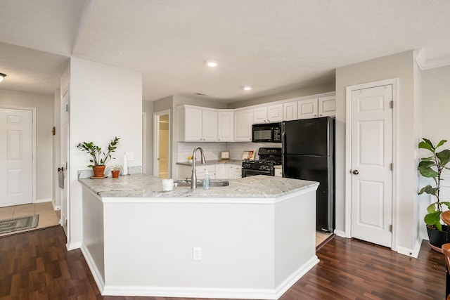 kitchen with sink, white cabinetry, black appliances, dark hardwood / wood-style flooring, and kitchen peninsula