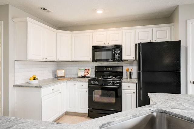 kitchen featuring backsplash, white cabinets, light tile patterned floors, and black appliances