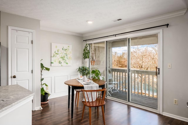 dining room featuring dark hardwood / wood-style flooring, ornamental molding, and a textured ceiling