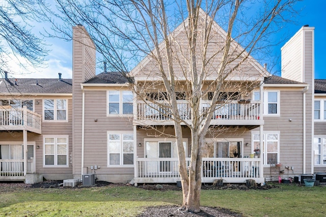 back of property with central AC, a balcony, and a lawn