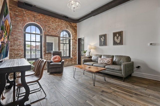 sitting room with brick wall, a chandelier, and wood-type flooring