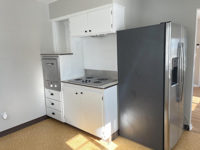 kitchen featuring stainless steel refrigerator with ice dispenser, electric stovetop, white cabinetry, and tasteful backsplash