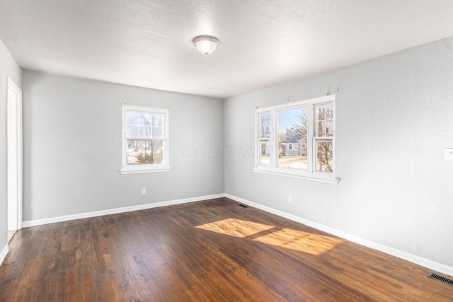 empty room featuring dark hardwood / wood-style flooring and a textured ceiling